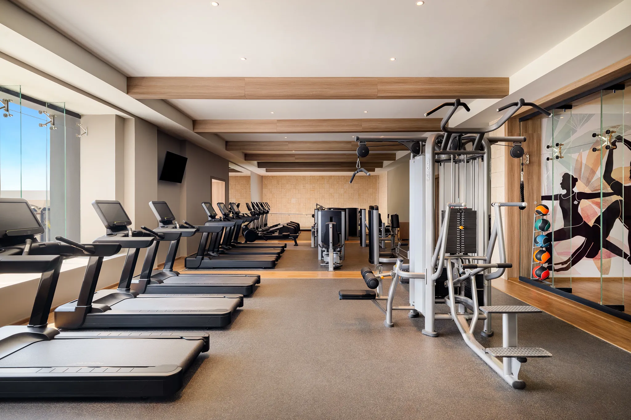 Modern fitness center at Secrets Tides Punta Cana with treadmills, strength machines, and spacious workout area.