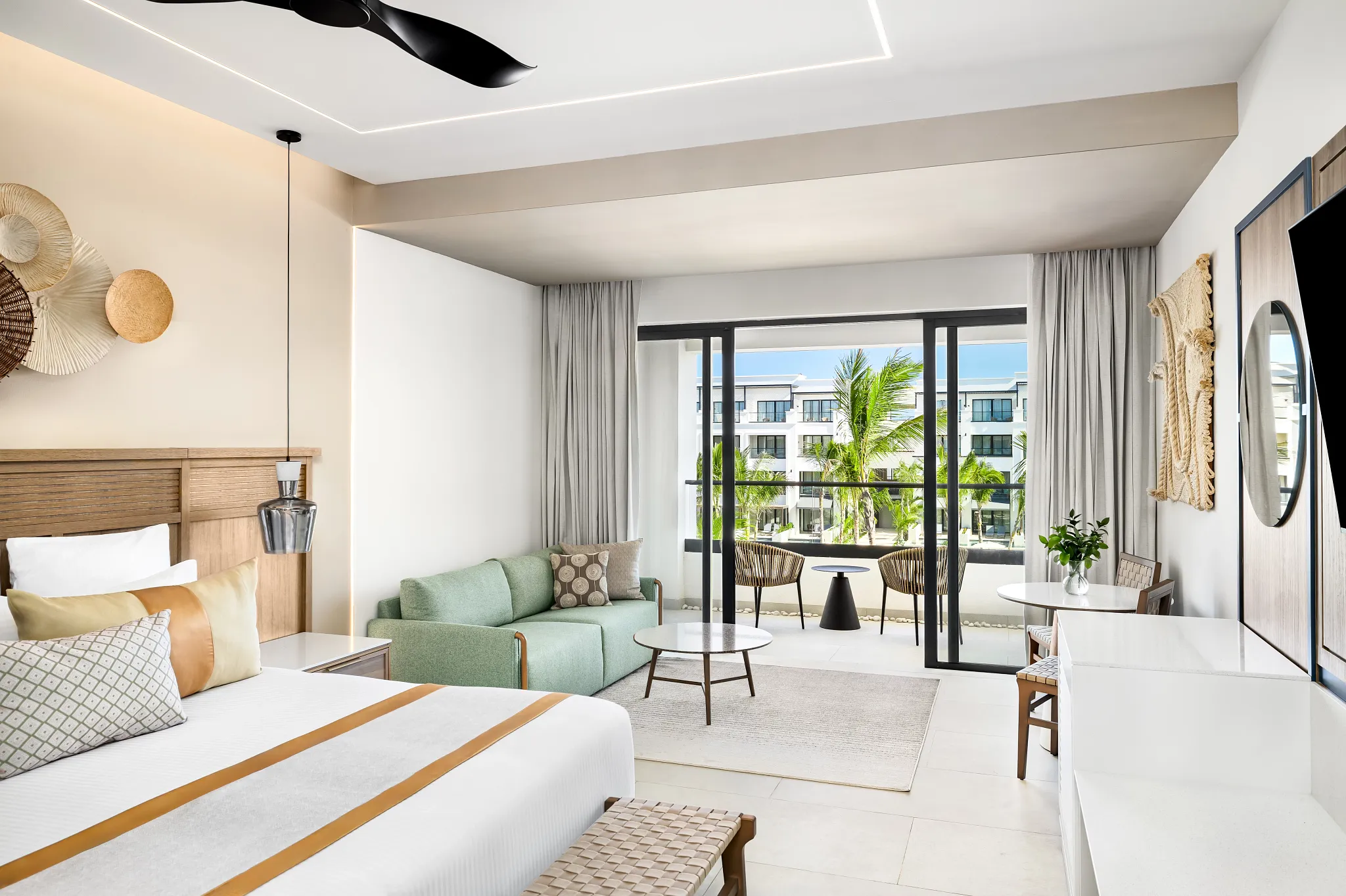 Junior Suite Garden View with king bed, seating area, and balcony overlooking tropical gardens at Secrets Tides Punta Cana.